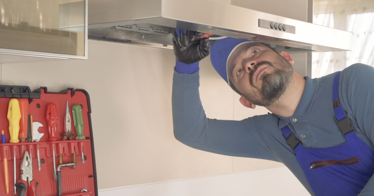 A technician prepares a commercial exhaust hood for a professional deep clean.